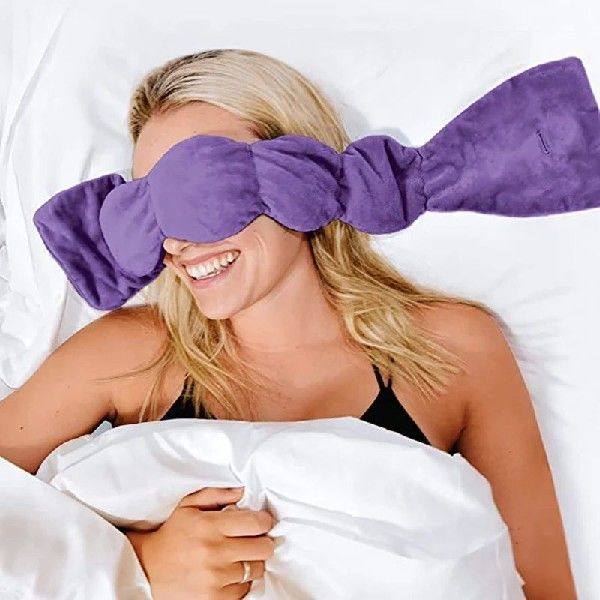 Woman wearing a purple eye mask in bed